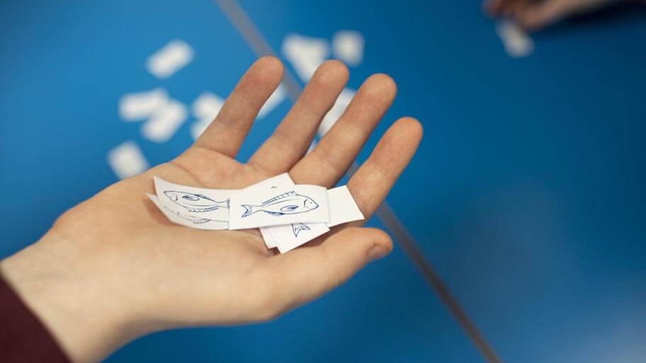 A student learning about ocean literacy. Their hand is holding a cut out of a paper fish.