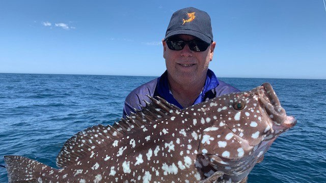 man on boat holding large fish