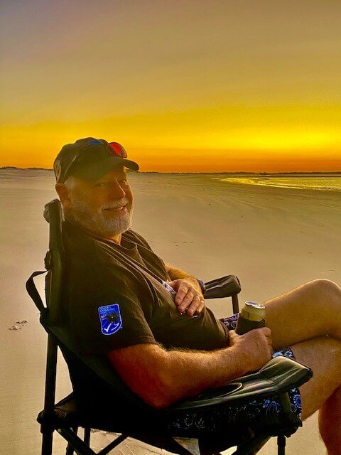 man sitting on chair on beach at dusk