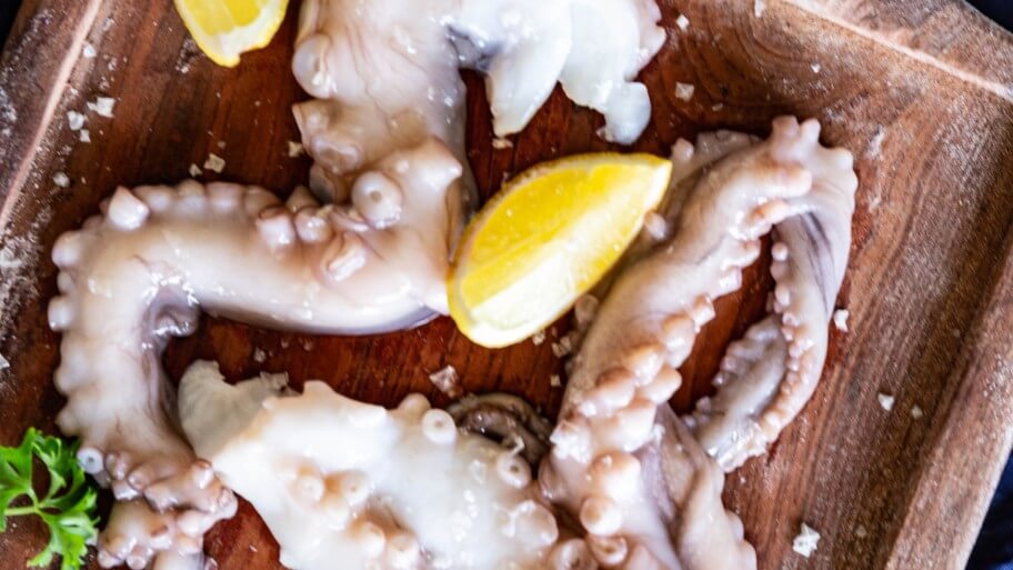closeup birds eye view of octopus on a plate with lemon