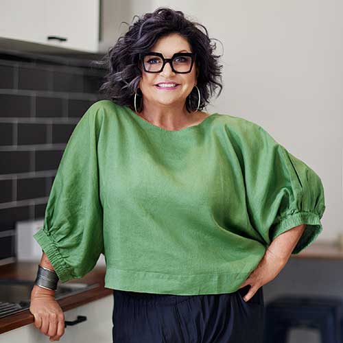 Woman wearing green blouse black-rimmed glasses and hoop earrings