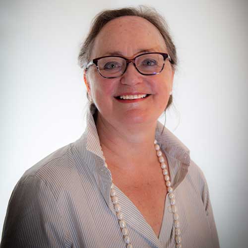 Woman wearing glasses, a striped shirt and long pearl necklace