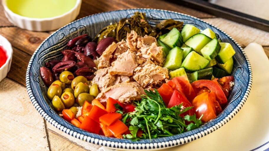 Hearty tuna bowl with variety of veggies, greens and olives.