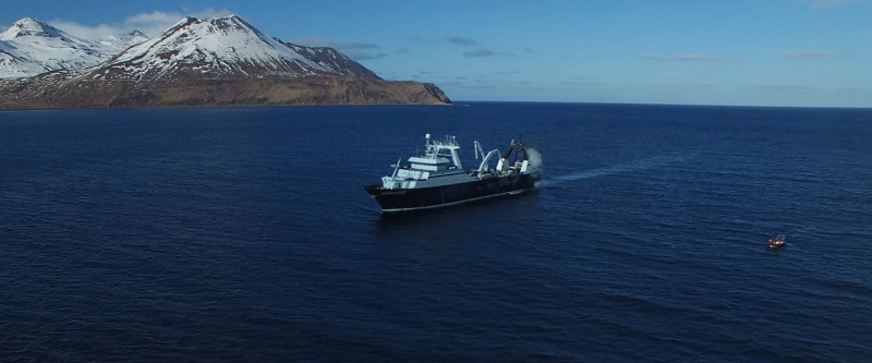 fishing vessel on ocean next to mountains