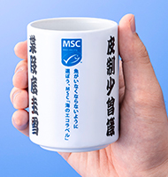 「魚偏のない漢字」を載せたキャンペーン特製湯呑みを手に持った写真