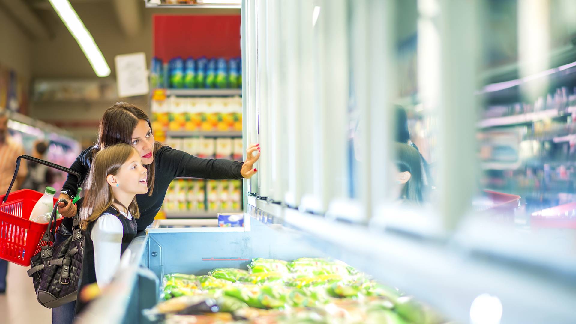 Woman and daughter choosing frozen food in supermarket