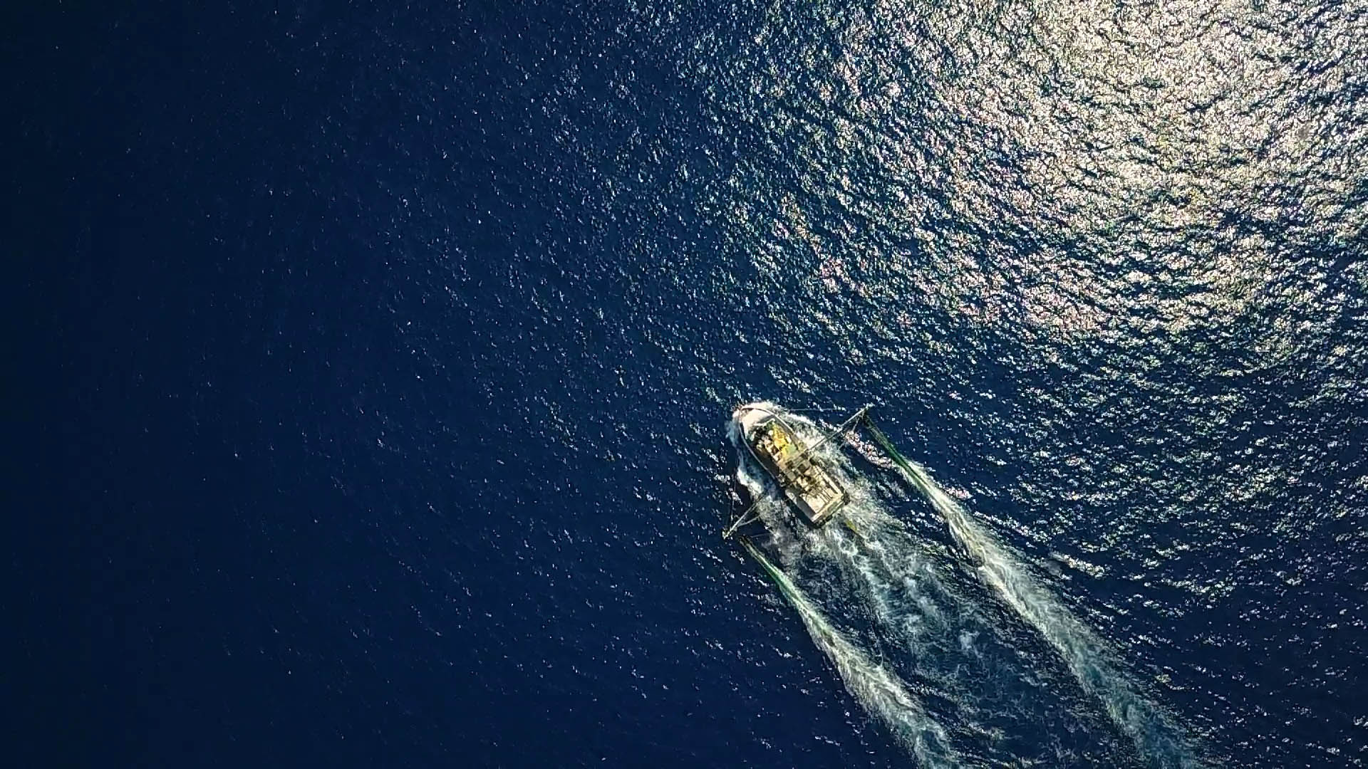 Aerial view of trawler vessel moving across water