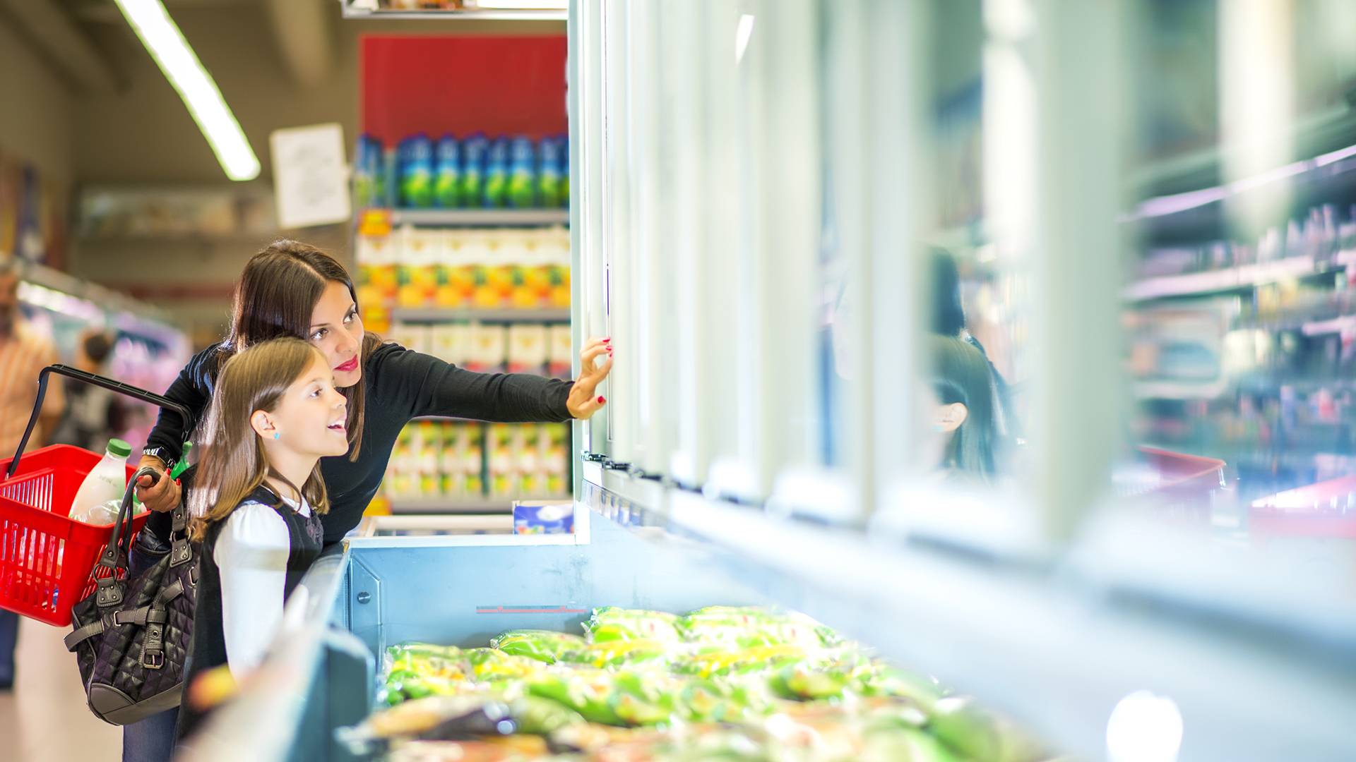 Woman and daughter choosing frozen food in supermarket
