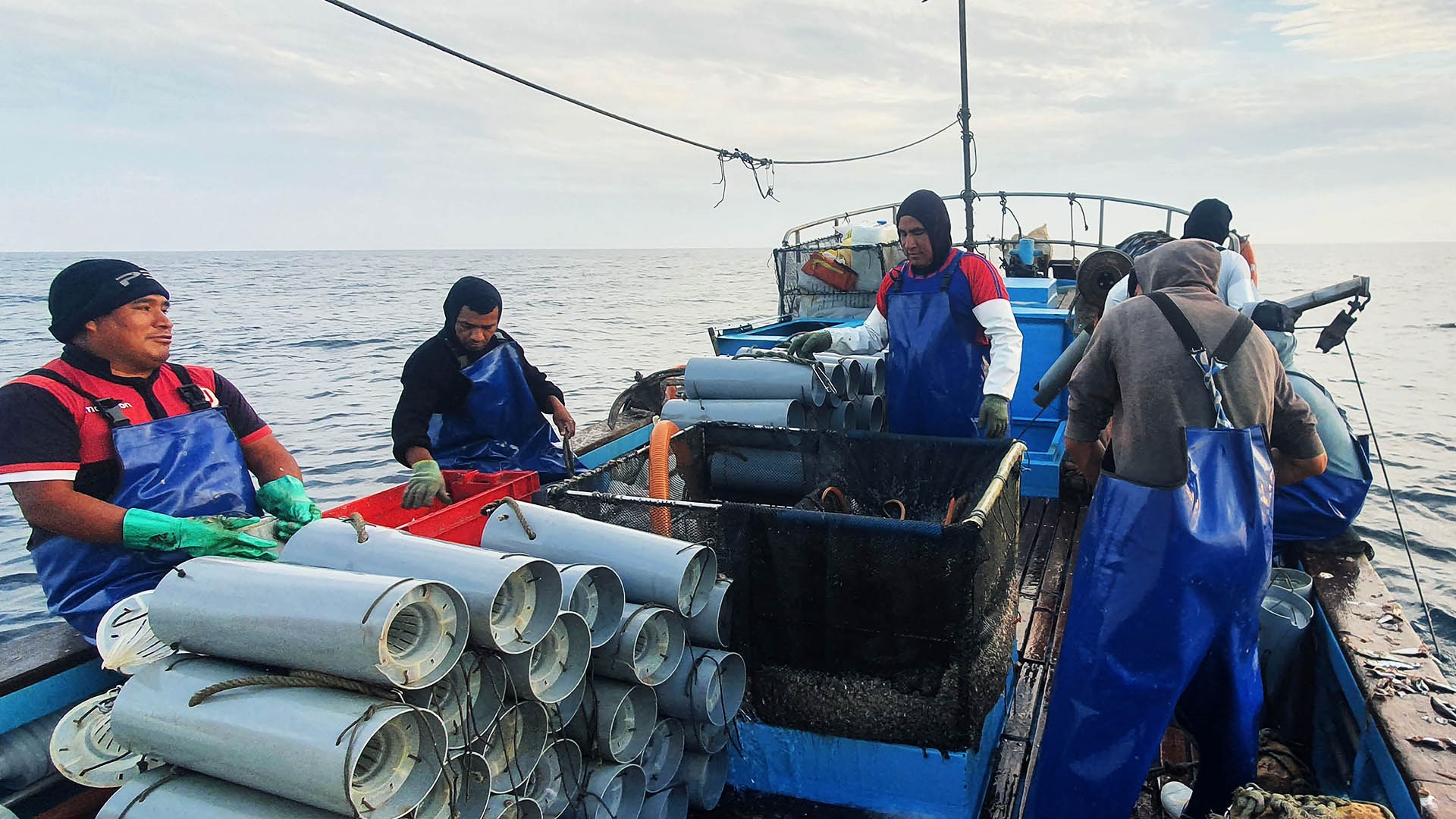 Four fishers on small boat with eel traps