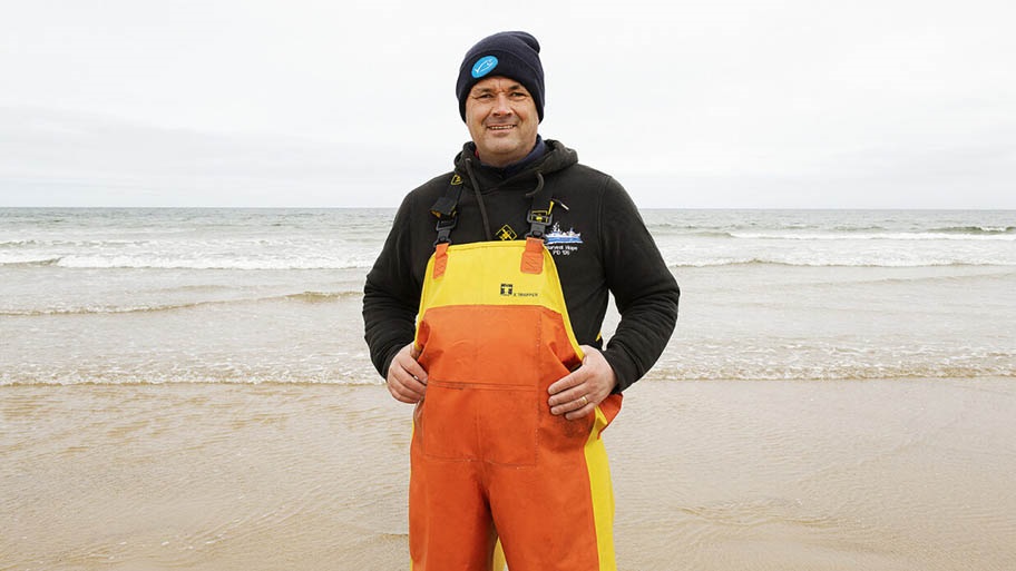 Portrait of fisherman in yellow and orange overalls on beach