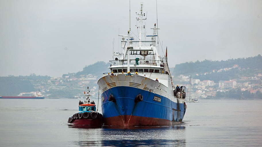 Large fishing vessel on still water in port, with foggy background