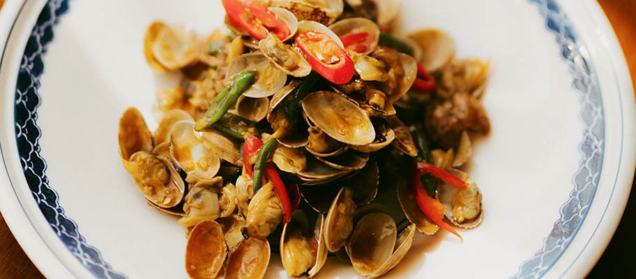 Bowl of clams with sliced chilis from above.