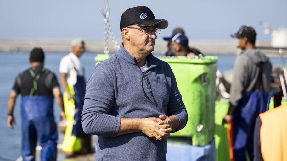 Francisco Santos, captain of the Iberian sardine vessel Vitória Coentrão on port in front of other fishers, Portugal