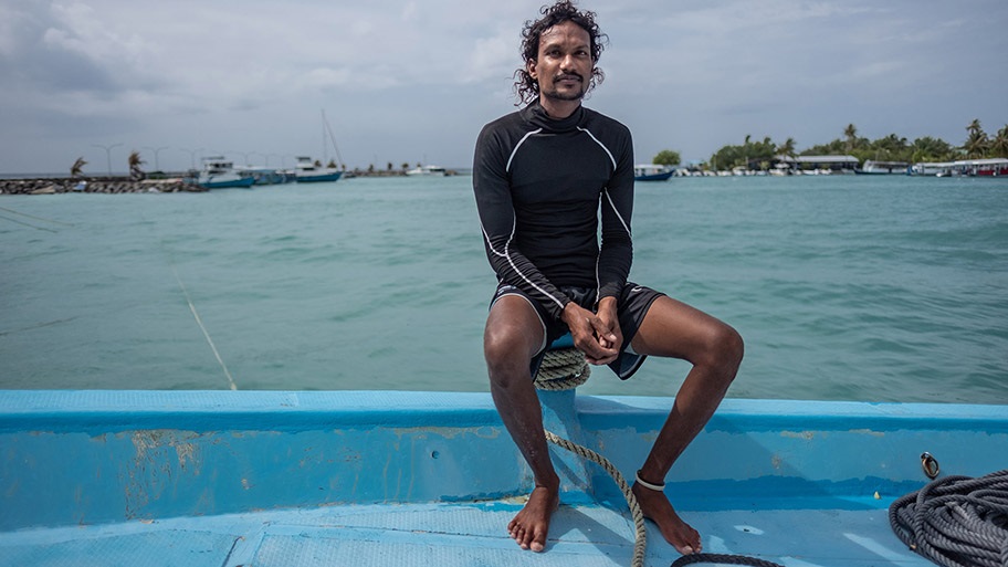 Maldives tuna fisher, Ibrahim Humaid sitting on edge of small boat