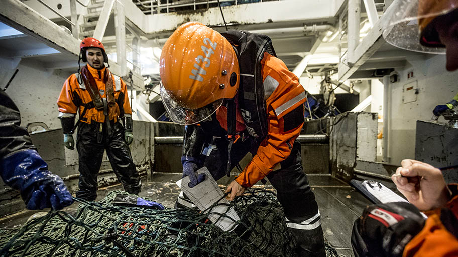 Men in orange waterproofs and helmets on boat with data-collecting devices