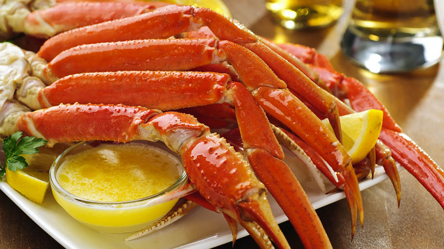 Snow crab legs on dish with lemon wedges and small pot of sauce