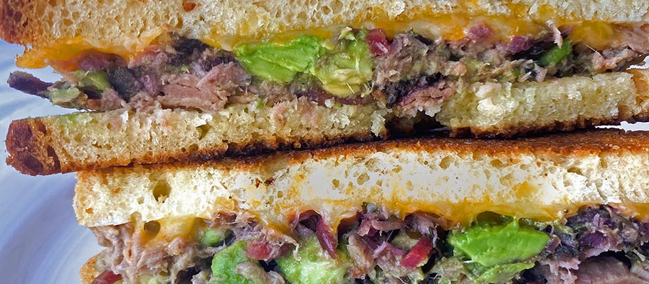Close-up of tuna melt with avocado in white toasted bread sandwich