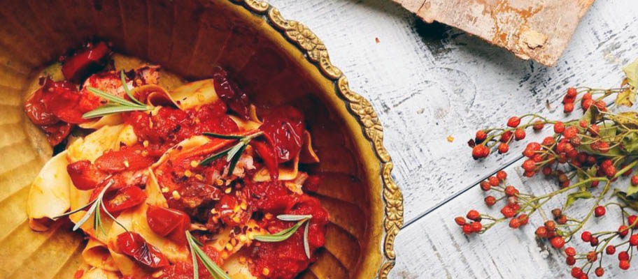 Lobster meat with pasta in wooden bowl with cutlery on wooden board 