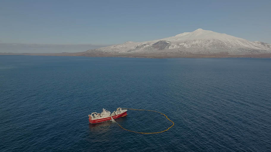 Large boat with net cast and snowy mountain in the distance