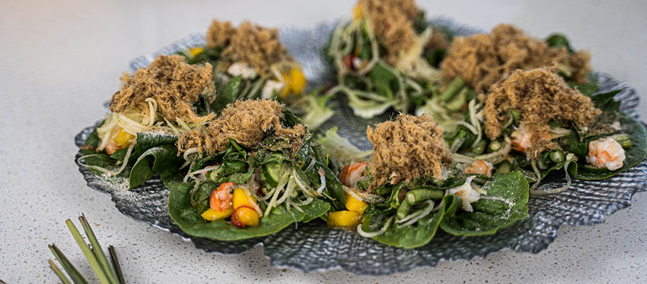 Prawns with leaves and mango pieces on dish