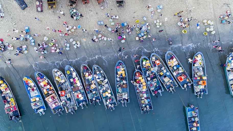 Aerial view of beach market in China with colourful crates on wooden boats