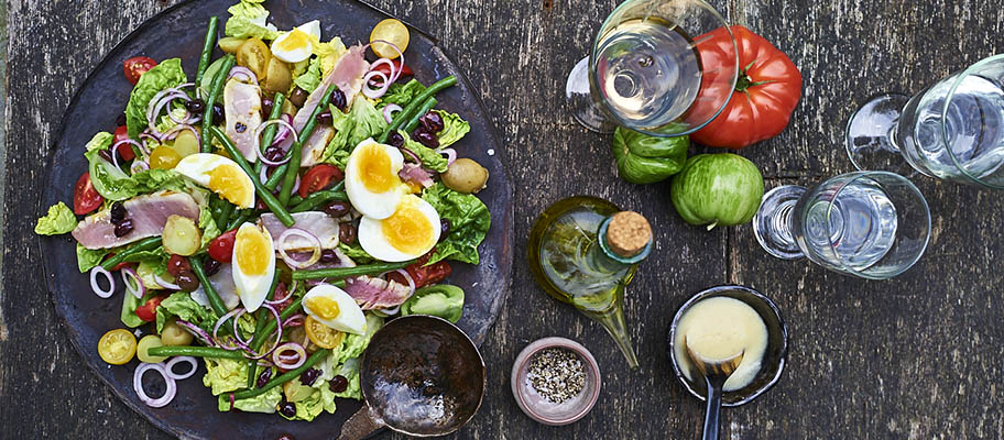 Aerial view of tuna salad on wooden table with wine glasses and bell peppers