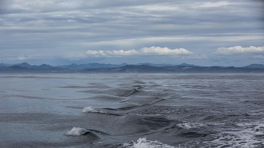 Sea with small waves and mountains and clouds on horizonn
