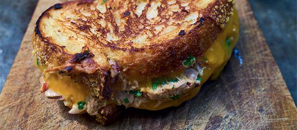 Tuna melted between slices of toast on wooden chopping board