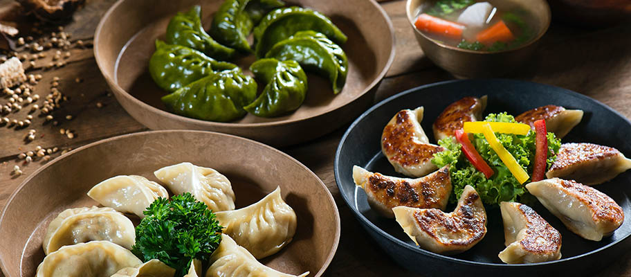 Three bowls with different types of Chinese dumplings on table 