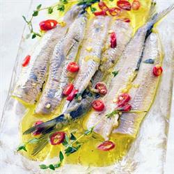 Sardines on a plate with red chillies and yellow sauce