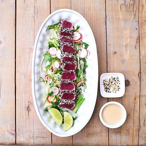 Serving suggestion for tuna tataki - tuna slices positioned in a line down the centre of a long plate