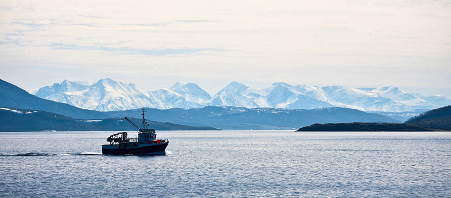 Fishing boat on still water with snow-capped mountains behind