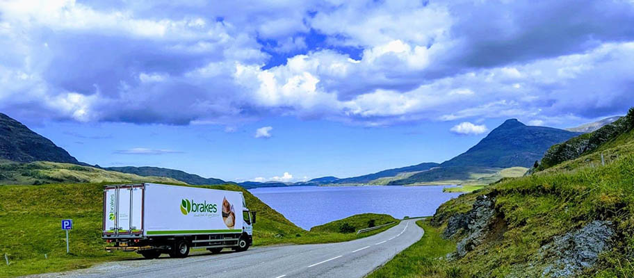 Delivery van parked on winding road, surrounded by water and hills