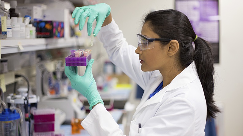 A scientist examining a vial.