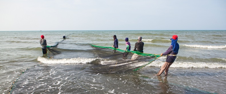 Filipino fishers with a net on the shore.