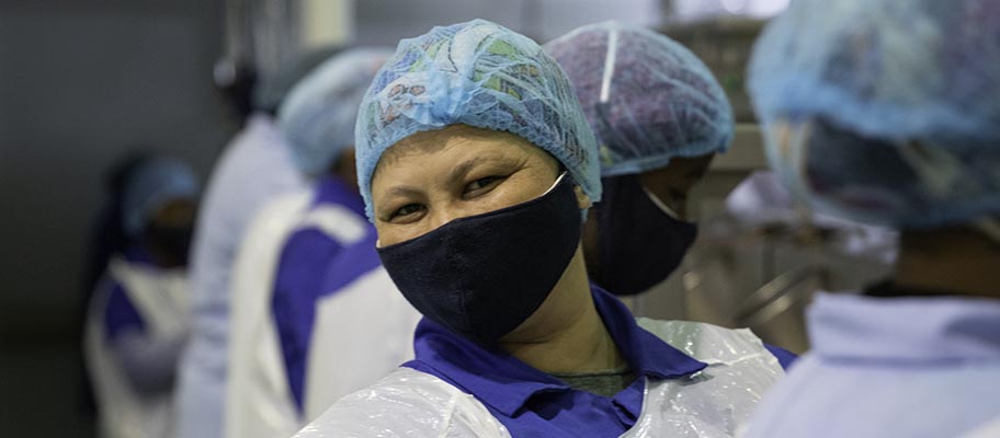 Woman in facemask and hair net looking at camera