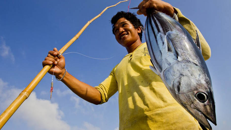 Un uomo regge un tonno pescato con canne e lenza in Indonesia