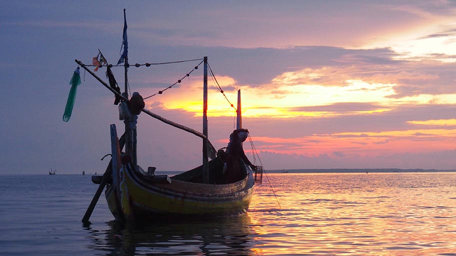 Small fishing boat on still water at sunset