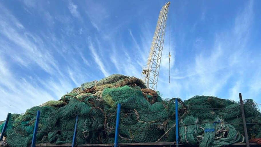 Pile of old trawl fishing nets with crane behind