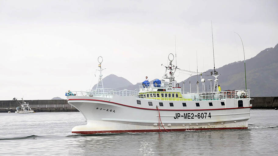 Fishing vessel returning to port, with mountains behind