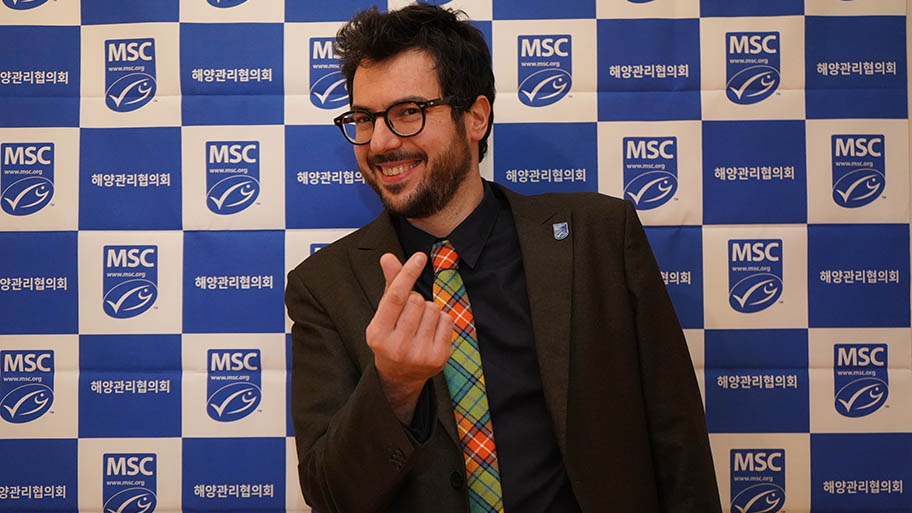 Chef Fabrizio Ferrari in suit and bright tie, with MSC logo background