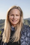 Woman with long hair in gilet in front of hills