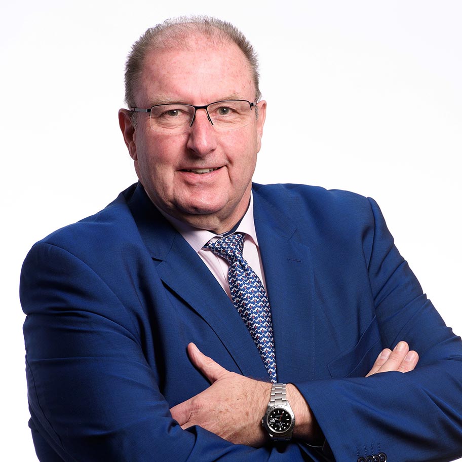 Head and shoulders image of man in blue suit with arms folded