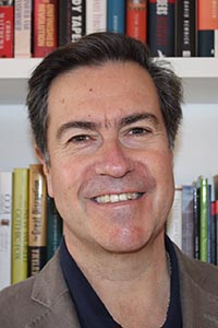Headshot of man in front of bookshelves: Sergio Yaksic