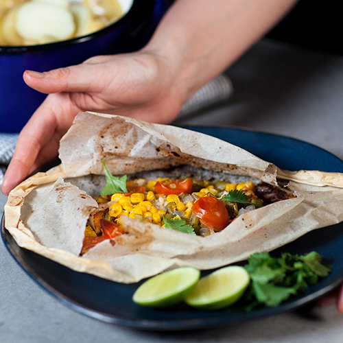 Person's hands presenting a cooked meal of pollock in parchment