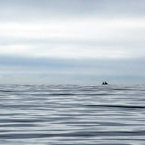 Boat on horizon on calm sea