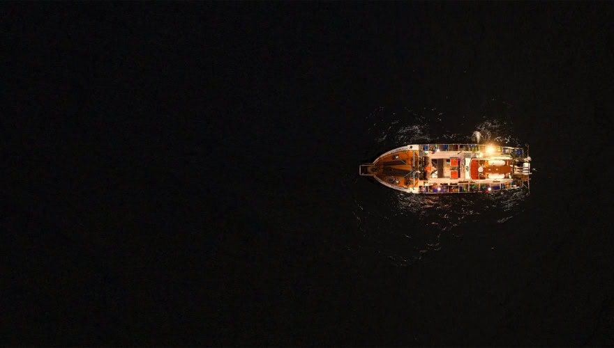 Aerial shot of squid fishing vessel on water at night