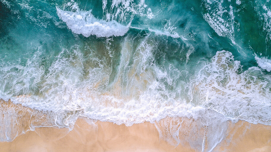Aerial view of ocean crashing on shoreline