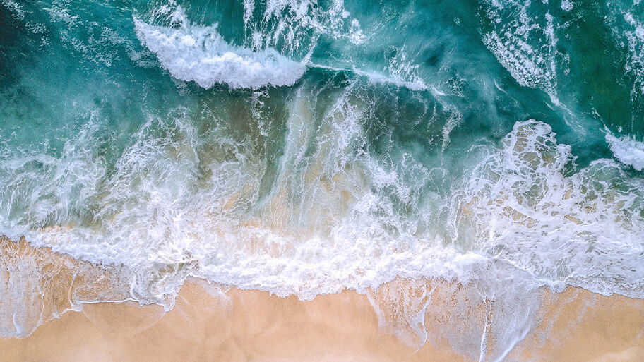 Aerial view of ocean crashing on shoreline
