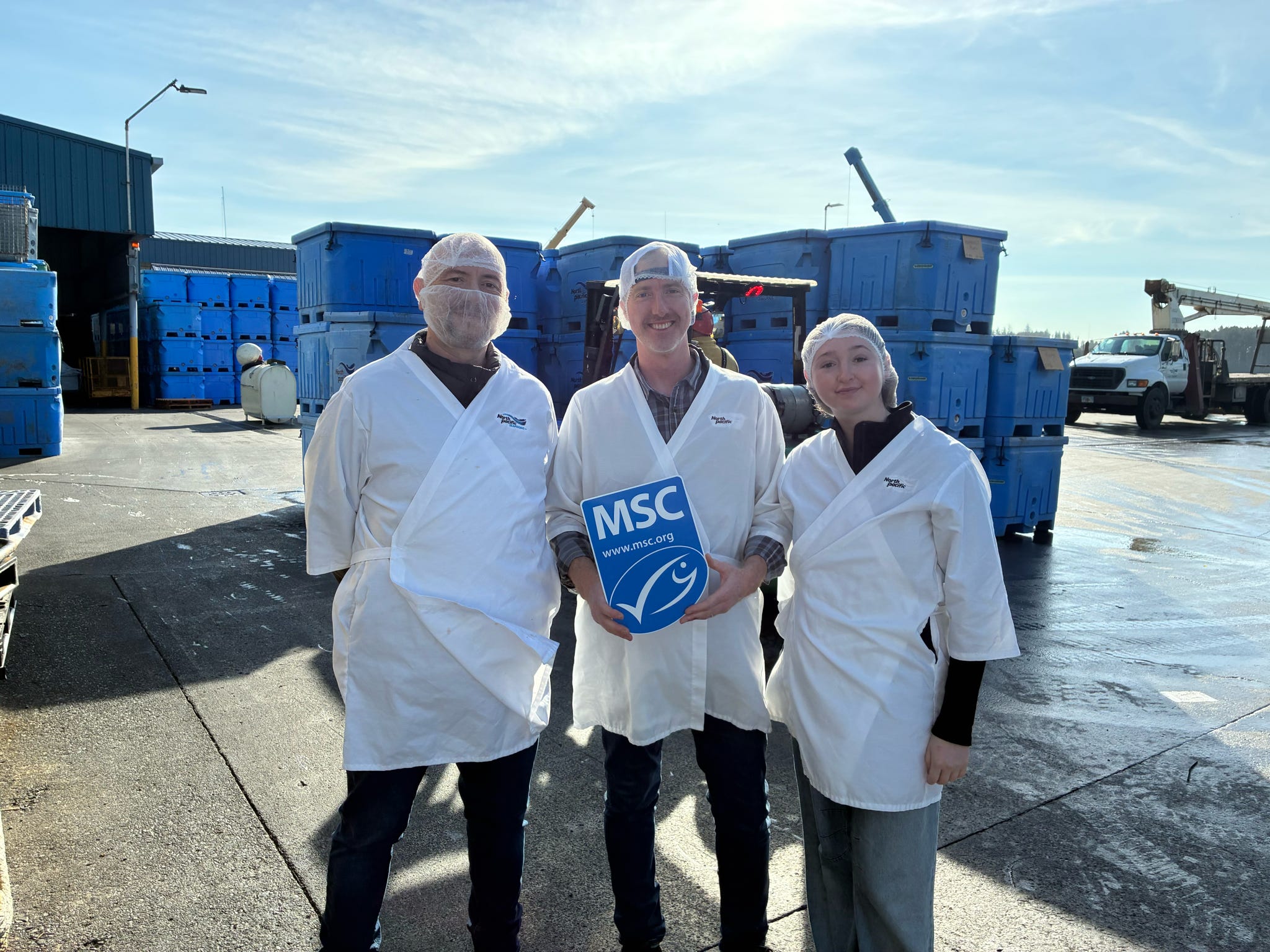 Group smiling in lab coats with the MSC blue fish label sign
